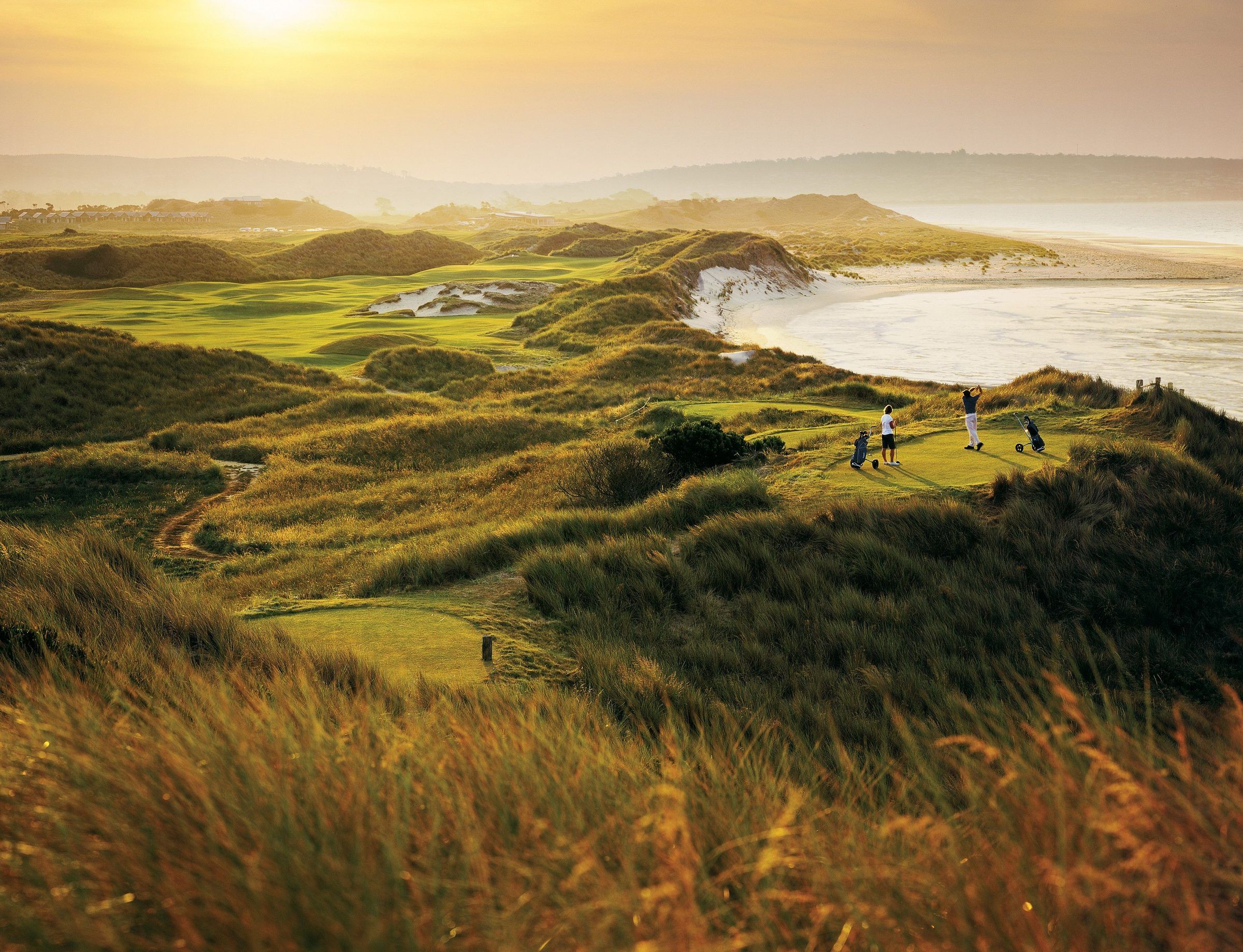 Golfers on a coastal links course in Tasmania at sunset